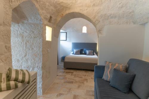 a bedroom with a bed and a couch in a room at CANTALANOTTE Luxury Trulli Resort in Cisternino
