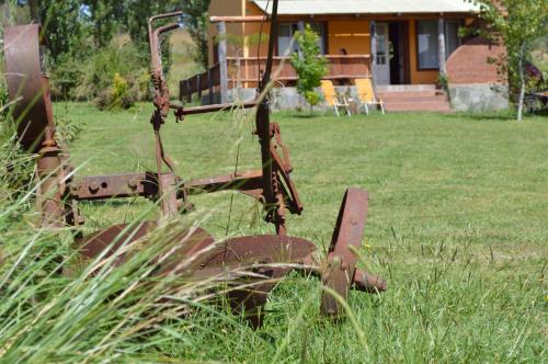 an old tractor in the grass in front of a house at Complejo Dulcería El Cazador y cabañas in Tandil