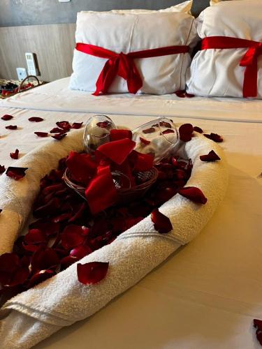 a bed with red rose petals on it at Pousada Maré do Francês in Praia do Frances