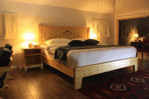 a bedroom with a large bed with a wooden headboard at Albayt Private Camp in Wadi Rum
