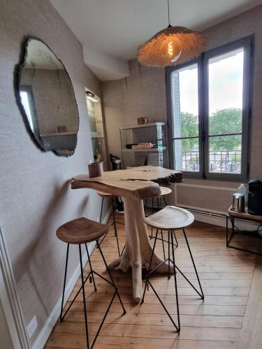 a kitchen with a table with stools and a mirror at La Villa des Tendances in Soissons