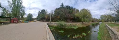 a road next to a river with trees and a building at Bajo el Roble in El Volcán