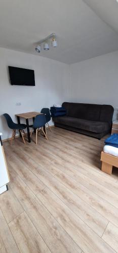 a living room with a black couch and a wooden floor at PokojeNaSpacerowej in Gąski