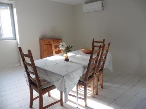 une table de salle à manger avec un vase de fleurs dessus dans l'établissement Appartement dans maison en pierre proche sortie autoroute A6, à Saint-Martin-Belle-Roche