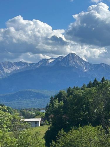a view of a mountain range with a house and trees at Penthaus am Südhang in Velden am Wörthersee