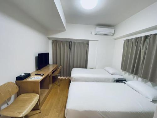 a hotel room with two beds and a desk at 嵐 Arashi BNB 大国町 No8113 in Osaka