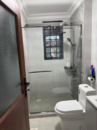 a bathroom with a shower with a toilet and a glass door at Mirenbe apartments in Nalakonge