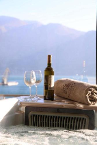 a bottle of wine and two glasses on a table at The Bayview apartment in Donji Morinj