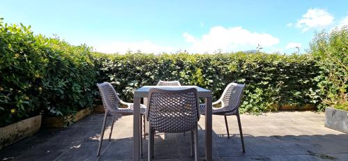 deux chaises et une table devant une haie dans l'établissement Studio Dolce & Vita A1 avec piscine et terrasse, à Propriano