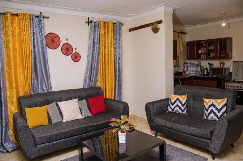 a living room with two chairs and a couch at Muggiez Vacation Homes in Kampala