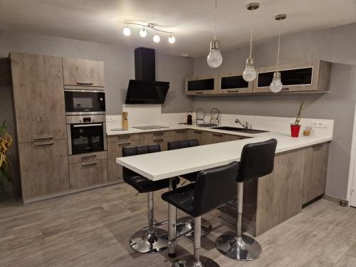 une cuisine avec une table blanche et des chaises noires dans l'établissement p'tite maison de PH, à Pont-Hébert