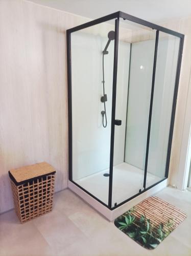 une cabine de douche en verre dans une pièce avec un panier dans l'établissement Le refuge de la source, à Bussang