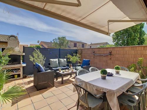 a patio with a table and chairs and an umbrella at Maison "Havre de Paix" dans résidence avec piscine in Vias