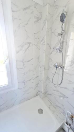 La salle de bains est pourvue d'une douche et de murs en marbre blanc. dans l'établissement Charmant logement entre la gare et le centre-ville, à Lorient