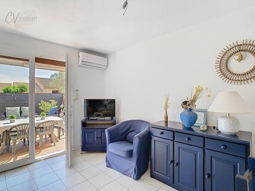 un salon avec une chaise bleue et une télévision dans l'établissement Maison 