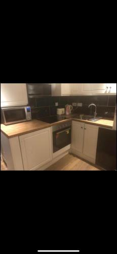 a kitchen with white cabinets and a sink and a stove at Luxurious Apartments at Beech Grove in Halifax