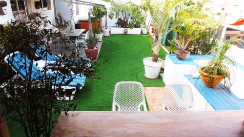 a patio with chairs and a green yard with plants at Un petit coin de paradis à Ouakam-Mamelles in Dakar