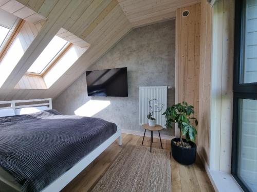 a bedroom with a bed and a flat screen tv at Osada Miłojeż - całoroczne Domy Premium w Borach Tucholskich, Jacuzzi pod gwiazdami in Gostycyn