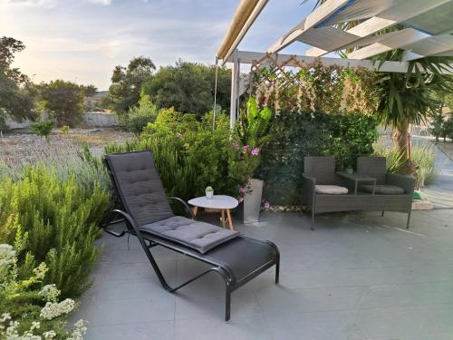 a patio with two chairs and a table in a garden at Cavo Prima Kiotari in Gennadi
