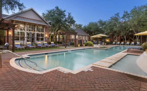 a pool at a resort with chairs and a building at Lavish Apartment near Houston Medical Centre in Houston
