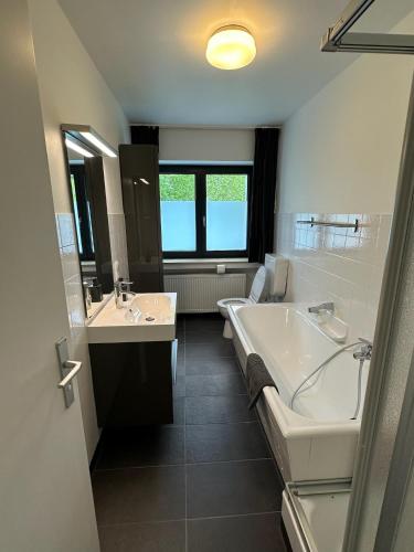 a bathroom with two sinks and a tub and a toilet at Villa Holgenbach - Penthouse und Ferienwohnung im Nationalpark Eifel in Schleiden