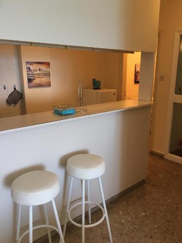 dos taburetes blancos sentados en un mostrador en una cocina en Alex Beach Apartment 51, en Lárnaca