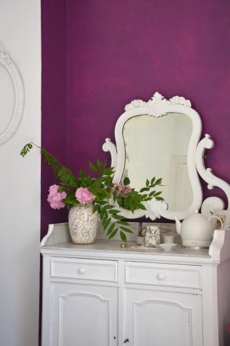 a white mirror on top of a white dresser with flowers at la maison in Libourne