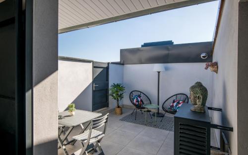 un patio avec une table et des chaises sur un balcon dans l'établissement Le minimaliste pk fibre clim terrasse, à Millau