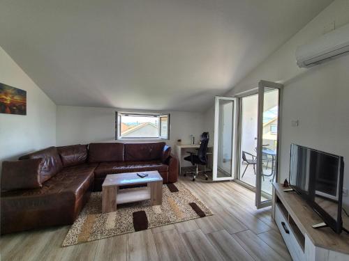 a living room with a brown leather couch and a television at Cozy, Fully Equipped, Free parking&Wifi, Quiet, 2BD in Podgorica