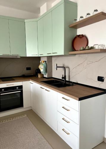 una cucina con mobili bianchi e un lavello di Puhiza Apartment a Lezhë (Alessio)
