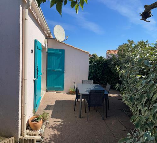 d'une terrasse avec une table et des chaises ainsi qu'une porte bleue. dans l'établissement Maison cosy près de la plage, à Bretignolles-sur-Mer