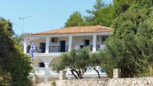 a large white house with a fence and trees at Anemone Blue Seaside Apartments in Zakynthos Town