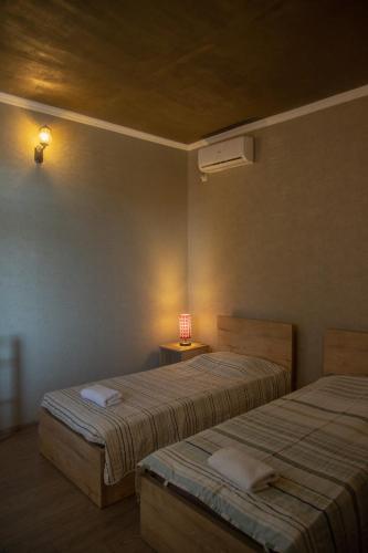 a bedroom with two beds and a light on the wall at Pavillion Guest House in Batumi