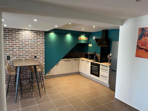 - une cuisine avec des placards blancs et un mur vert dans l'établissement Loft de la louve, à Villeveyrac