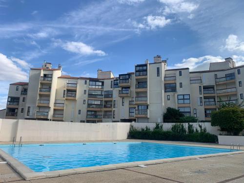 un immeuble d'appartements avec une piscine devant dans l'établissement Appartement quartier des Minimes avec piscine, parking, en bordure du port à La Rochelle, à La Rochelle