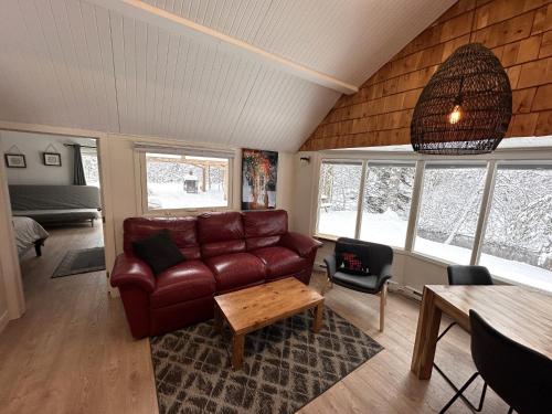 a living room with a leather couch and a table at Le refuge de la petite rivière in Saint Mathieu Du Parc