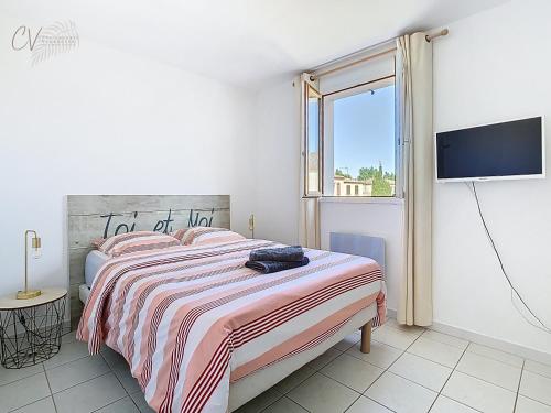 a white bedroom with a bed and a tv at Maison "Douceurs d'Été " Maison de vacances bord de mer à Vias plage - 600m de la plage et du Canal du Midi - Piscine résidentielle, wifi fibre, Activités et Loisirs in Vias
