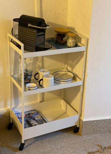 une étagère blanche avec de la vaisselle et des assiettes. dans l'établissement mon petit nid cosy, à San-Martino-di-Lota