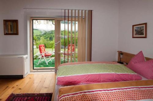 a bedroom with a bed and a balcony with chairs at Hütterhof in Grundlsee