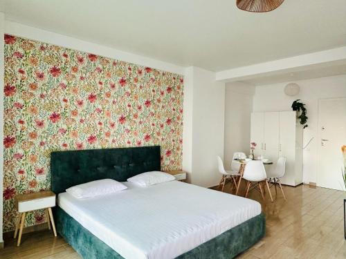 una camera da letto con un letto con una parete con accenti floreali di Bucuria Studios Mamaia Nord a Mamaia Nord - Năvodari