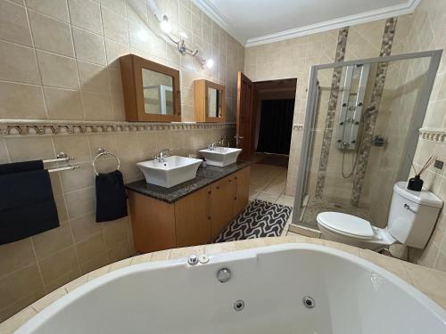 a bathroom with a tub and two sinks and a toilet at Fish Eagle Manor in Warmbaths