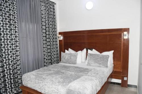 ein Schlafzimmer mit einem Bett mit hölzernem Kopfteil in der Unterkunft Jad Hotel Dschang in Dschang