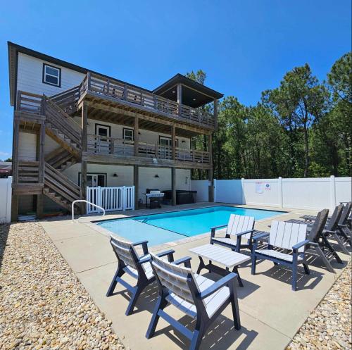 a house with a swimming pool with chairs and a deck at Sojourn Corolla 6 Bedroom POOL in Corolla