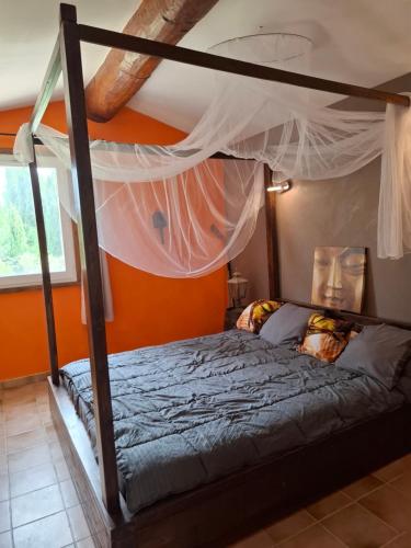 une chambre avec un lit à baldaquin avec un mur orange dans l'établissement couples AMOUREUX gde propriété 4000M2 avec 2 maisons indépendantes grande piscine privée clim, à Combas