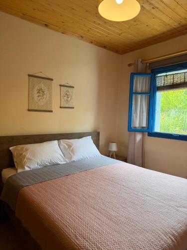 a bedroom with a bed with a blue window at Sotirias Beach House in Kalamos