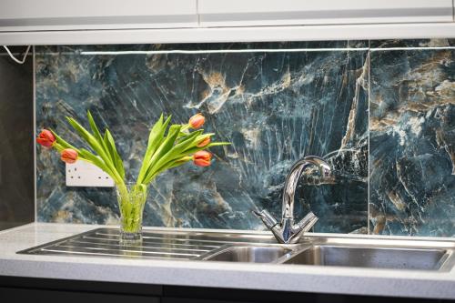 a vase of flowers sitting on a kitchen sink at Modern Family 3 bedroom house,Free Parking,Garden in Dagenham