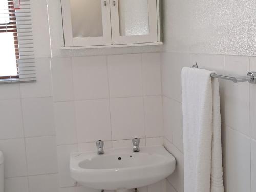a white bathroom with a sink and a towel at Bandile's cosy home in Honeydew