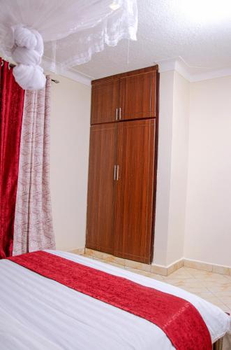 a bedroom with a bed and a wooden cabinet at Muggiez Vacation Homes in Kampala