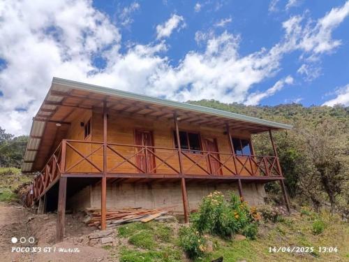 a wooden house with a balcony on a hill at Nido y Mirador El Condor Sierra Nevada Guican y El Cocuy in Güicán