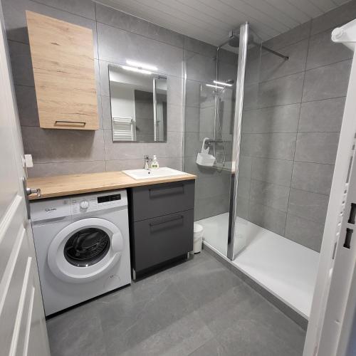 a bathroom with a washing machine and a shower at Reine de la plage in Fouesnant